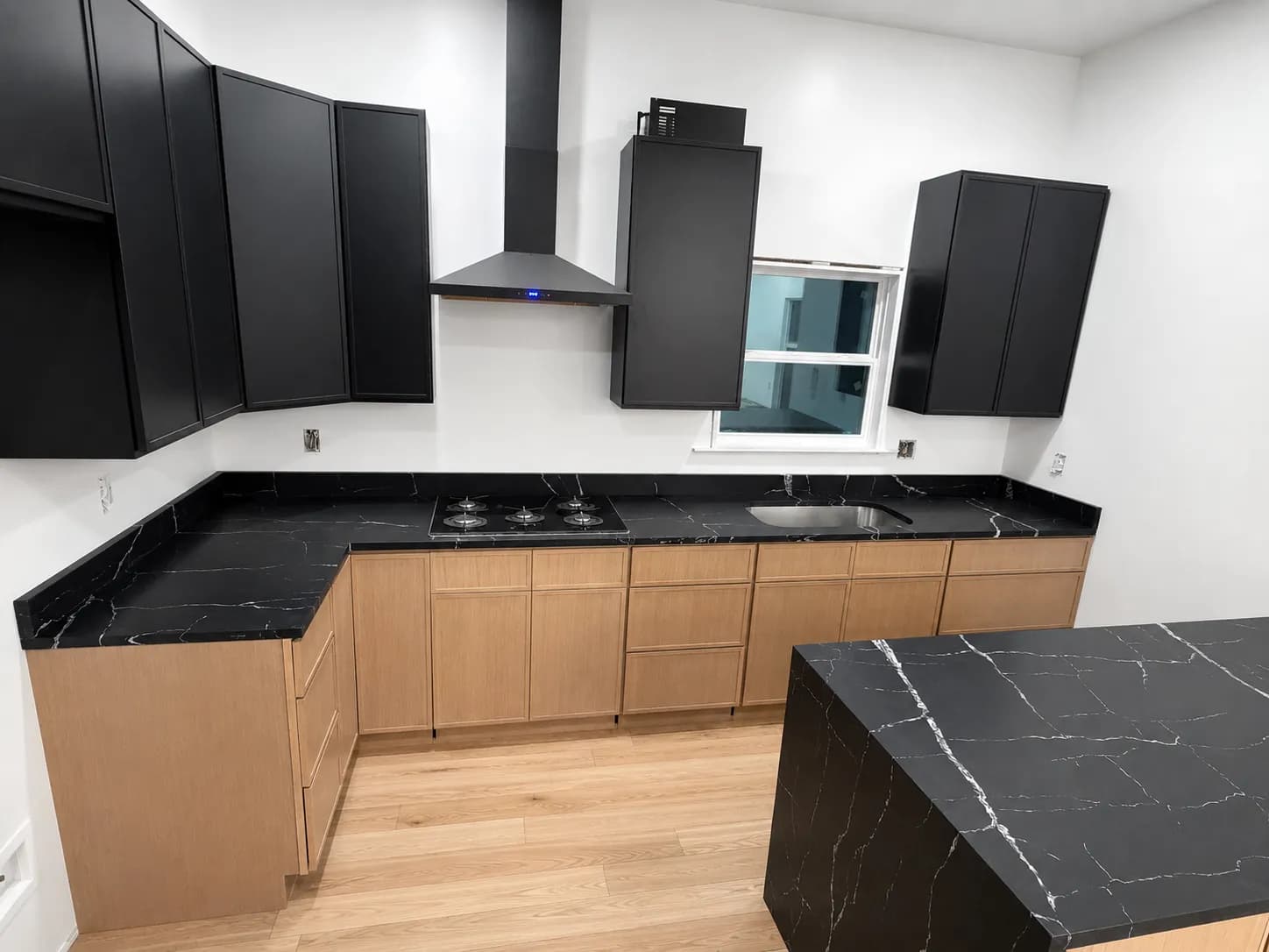 Dramatic black quartz kitchen with waterfall island